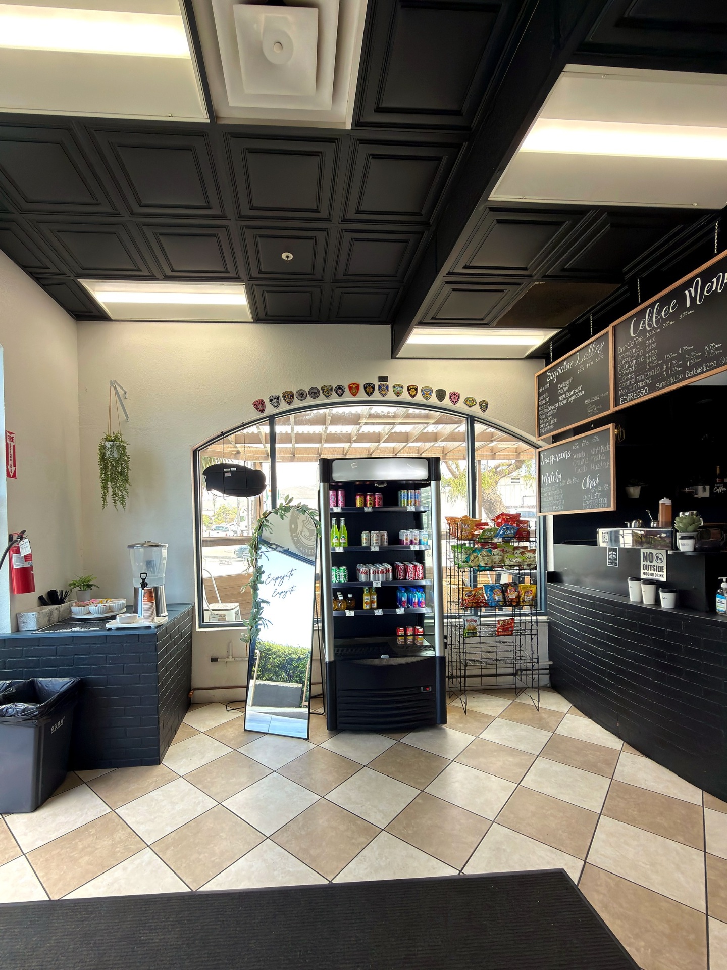 La Cafeteria interior with black coffered ceiling, cooler, and snack rack