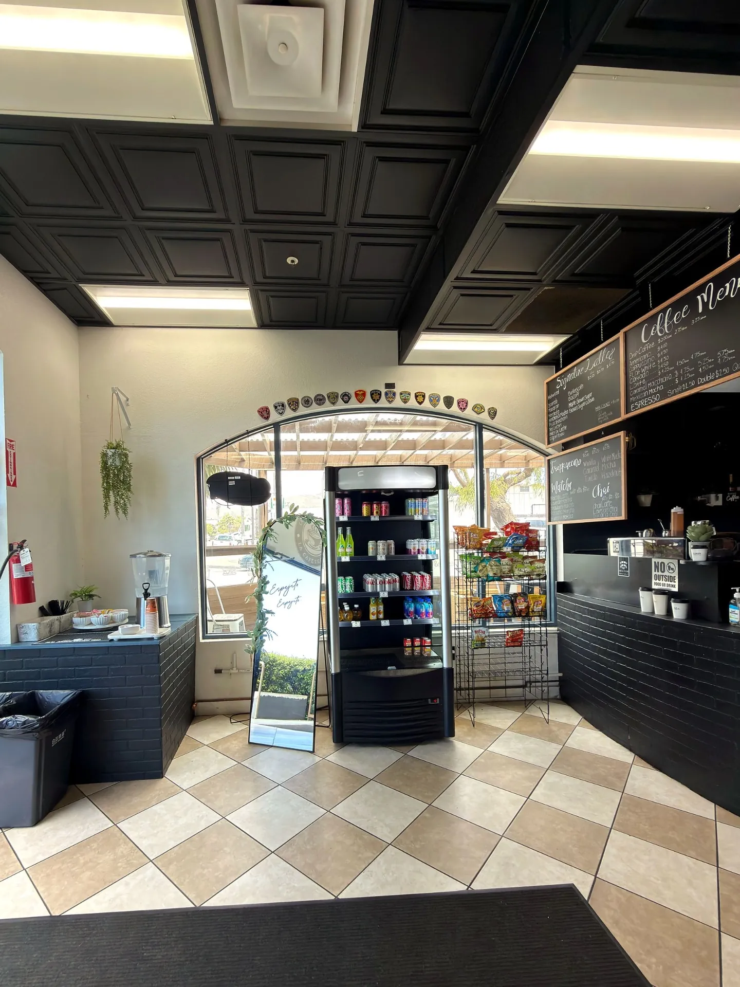 La Cafeteria interior with black coffered ceiling, cooler, and snack rack