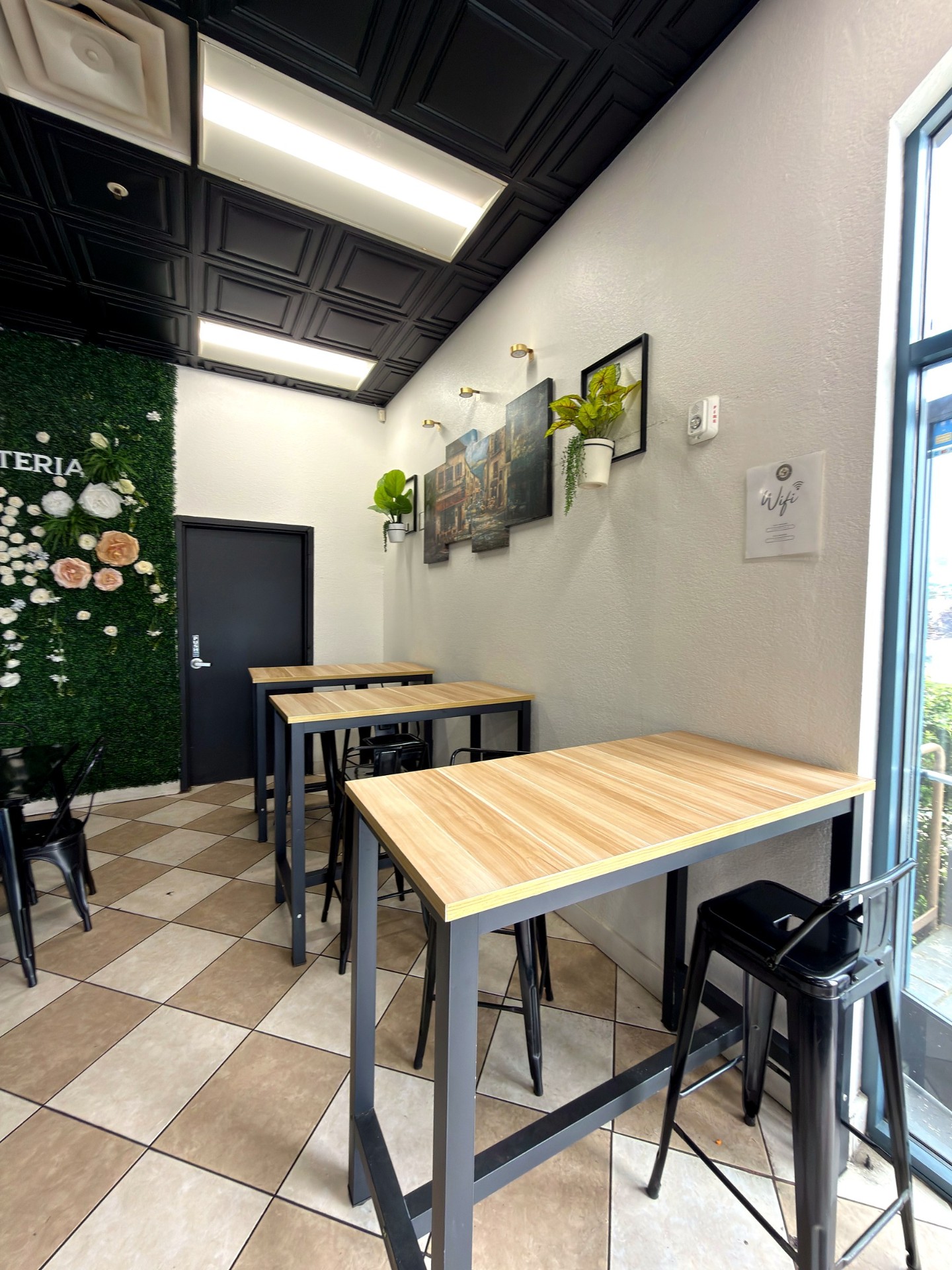 High-top wooden tables and stools in La Cafeteria's seating area